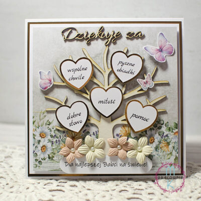 kartka kwadratowa na jej środku jest drzewo a na nim zamiast liści są złote serduszka a na nich serduszka białe z napisami: wspólne chwile, pyszne obiadki, miłość, pomoc, dobre słowo. Nad drzewkiem jest napis dziękuję za. Przy pniu drzewa są kwiatki a pod nimi napis: Dla najlepszej babci na świecie