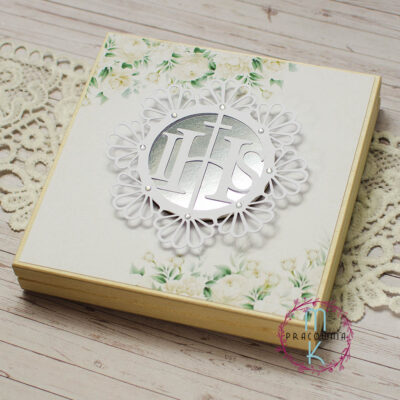 zaproszenie w drewnianym pudełku ozdobionym biało kremowym papierem, na środku ozdobna biała ramka z napisem IHS z dodatkiem lustrzanego papieru