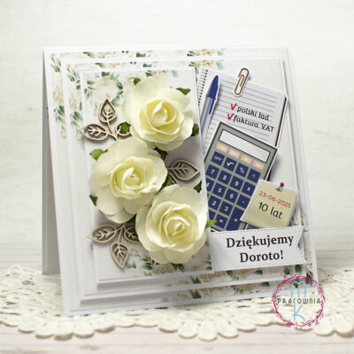 Po lewej stronie kartki znajdują się 3 kremowe przestrzenne róże otoczone listkami z tektury. Po prawej stronie są elementy nawiązujące do pracy księgowej i kadrowej: długopis, kalkulator, karteczka samoprzylepna, kartka zeszytowa na której można napisać np. faktura vat, polski ład albo coś innego czym dana osoba się zajmowała