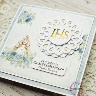 Kartka okolicznościowa z okazji 22. rocznicy święceń kapłańskich, w odcieniach błękitu, z grafiką złożonych dłoni do modlitwy i różańcem. Personalizowana, zapakowana z białą kopertą. Format kwadratowy.