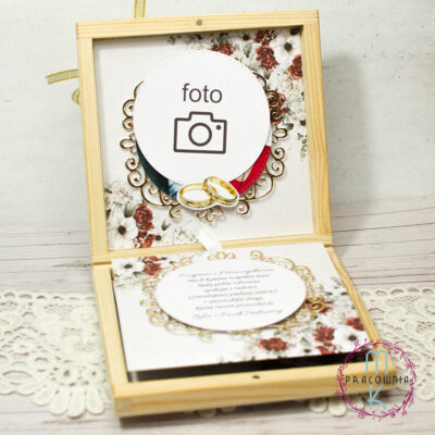 Pamiątka w drewnianym pudełku na złote gody. Pudełko jest otwarte, na górnej ściance jest zdjęcie Jubilatów, a w dolnej części pudełka za pomocą wstążki można rozwinąć kolejne kartki gdzie znajdują się życzenia, kartka z kalendarza