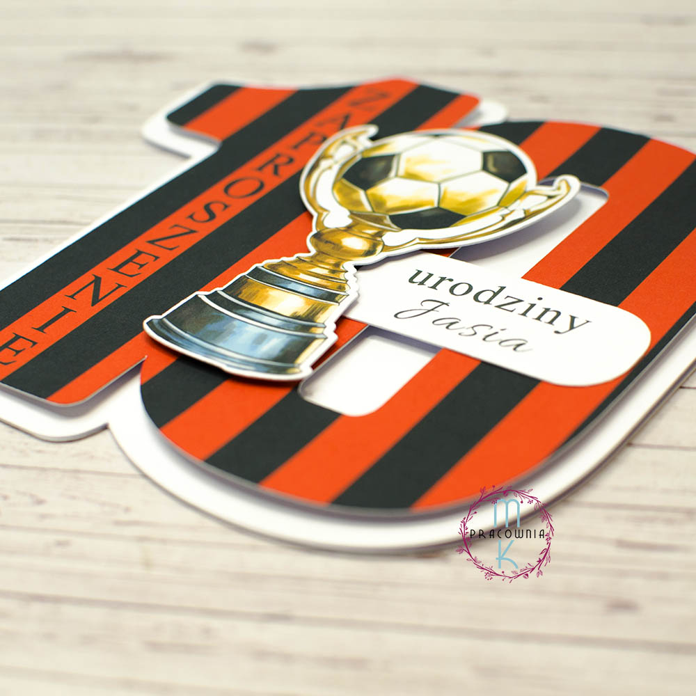 _DSC7049_www zaproszenie w kształcie cyfry 10 w kolorach biało czerwonych w paski. Na środku znajduje się puchar z piłką nożną, na prawo od niego napis Urodziny Jasia. Wzdłuż cyfry 1 znajduje się napis: Zaproszenie