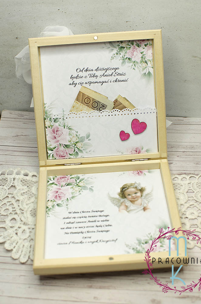 _DSC7227_www Środek drewnianego pudełka. Na górnej części jest cytat a pod spodem kieszonka na pieniądze. Kieszonka ozdobiona w dolnym prawym rogu różowymi serduszkami. Na dolnej części pudełka są życzenia z grafiką aniołka dziewczynki. Całość w tonacji białej z delikatnymi różowymi kwiatkami