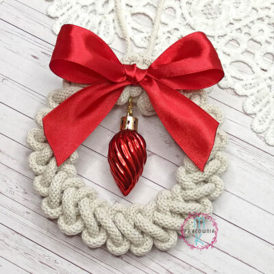 wianek z makramy z czerwoną wstążką i czerwoną bombką w środku