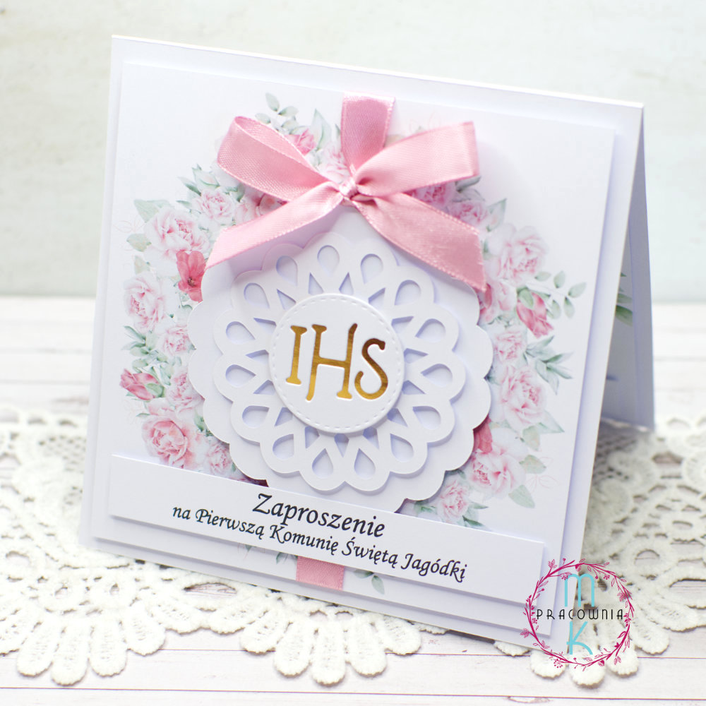 _DSC7669_www W centralnej części zaproszenia jest wianek z różowych kwiatów a wewnątrz niego jest złoty napis IHS. Całość przewiązana jest różową wstążką u góry zaproszenia