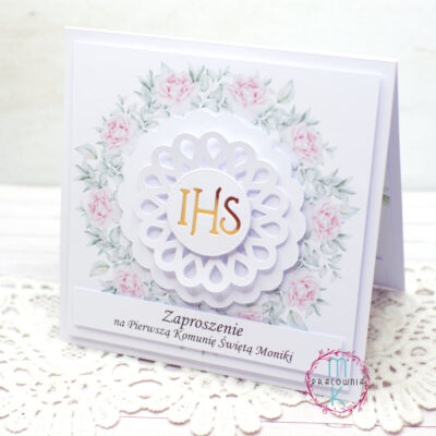 W centralnej części zaproszenia jest wianek z różowych kwiatów a wewnątrz niego jest złoty napis IHS.